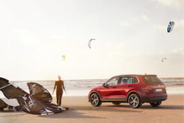 Picture of the Volkswagen Tiguan at the beach. A girl with a kite nearby. 